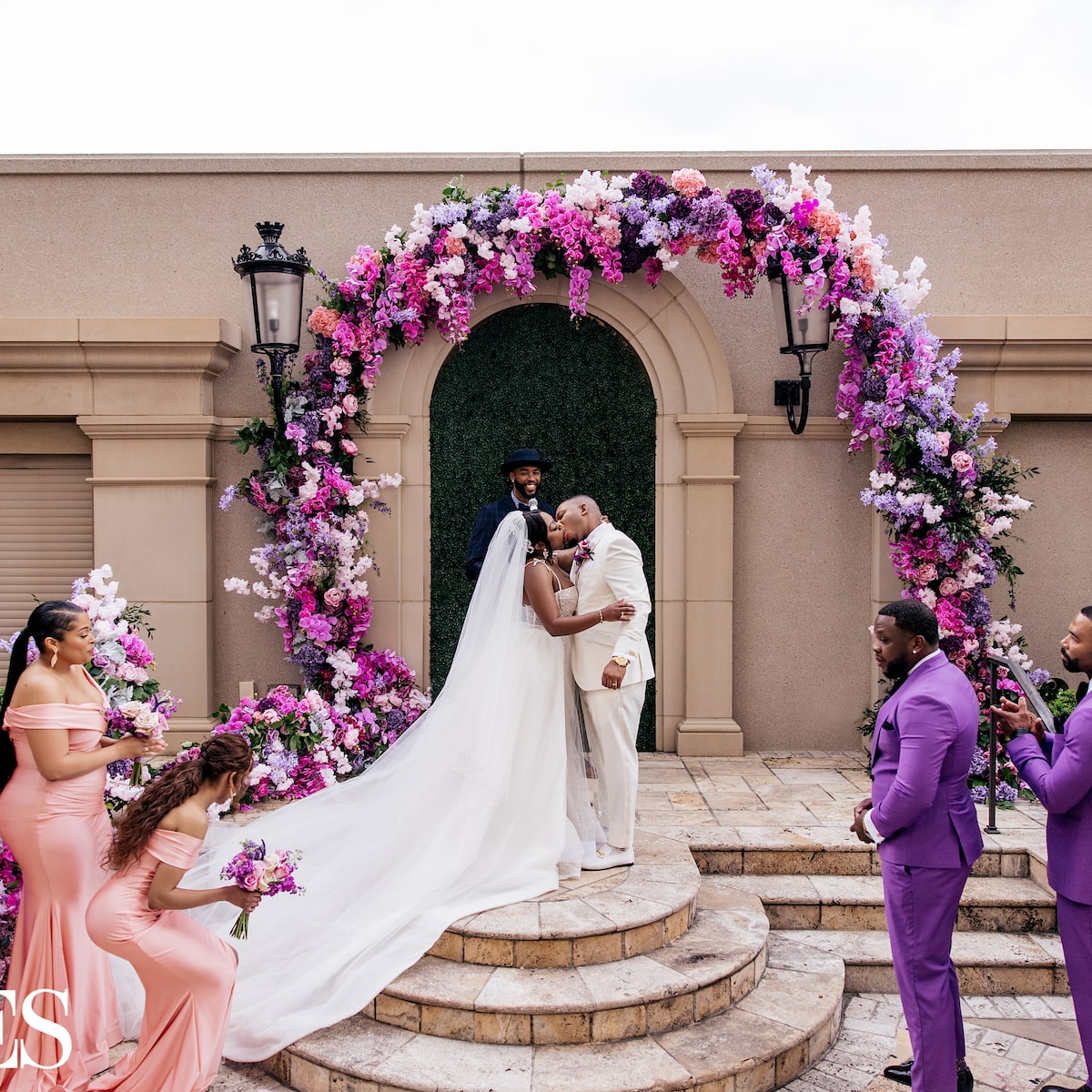 Newlyweds sharing their first kiss beneath a lush floral arch